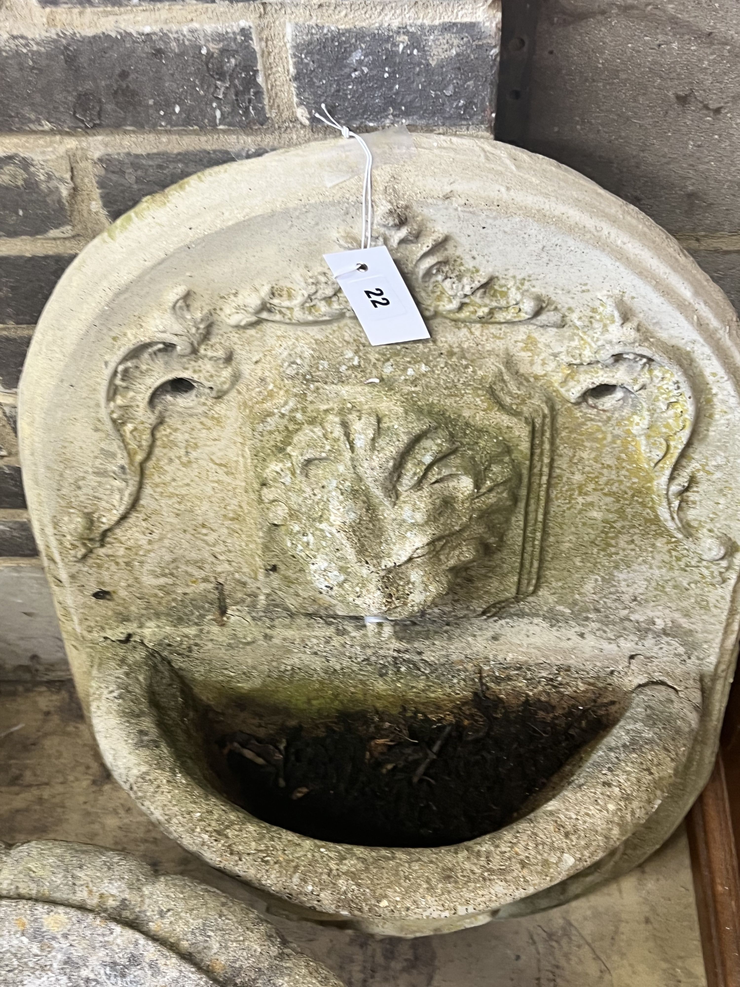 A reconstituted stone garden wall mounted water fountain, with lion mask spout, width 48cm height 70cm